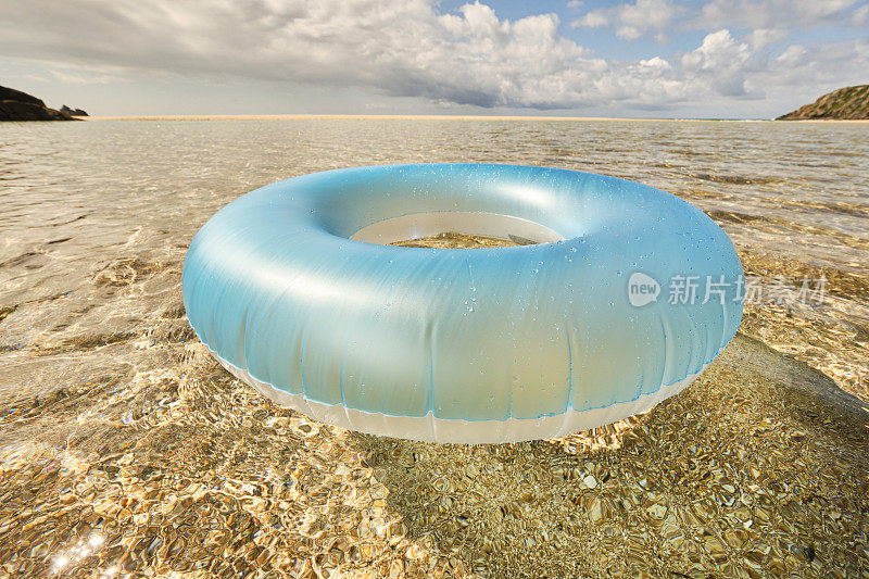 淡蓝色的橡胶圈漂浮在浅水清澈的海面上，在Pedn Vounder海滩，康沃尔在一个田园诗般的阳光明媚的六月天。